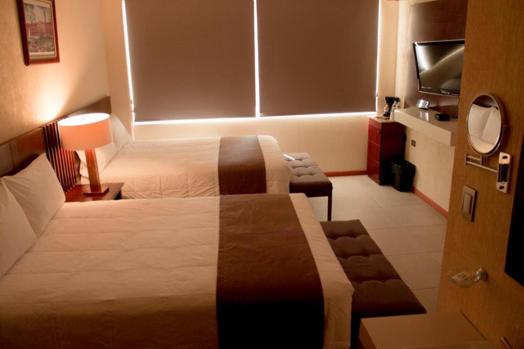 a hotel room with two beds and a television at Hotel Tlaxcala in Tlaxcala de Xicohténcatl