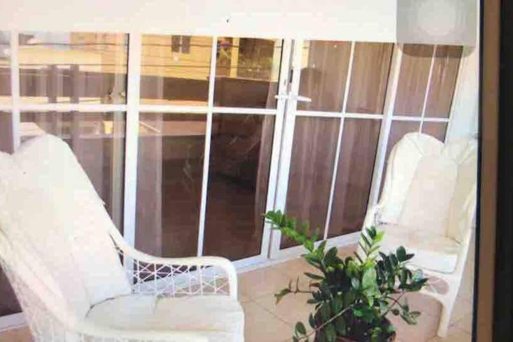 two white chairs and a plant on a window at Apartamento Los Anturios en Puerto Plata Bayardo in San Felipe de Puerto Plata