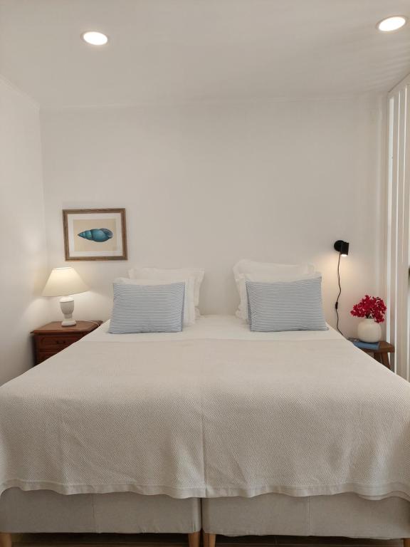 a bedroom with a white bed with two pillows at Estúdio Lagoa Azul in Vila Nova de Milfontes