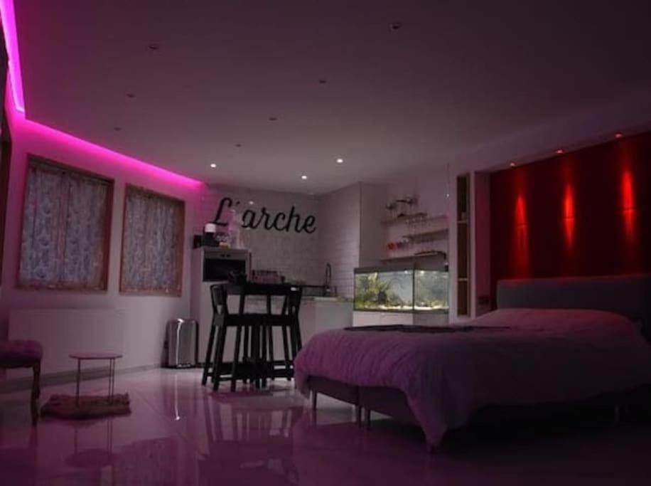 Schlafzimmer mit einem Bett und einem Tisch mit rosa Lichtern in der Unterkunft L'Arche Loft nid douillet - Spa privatif in Grenoble