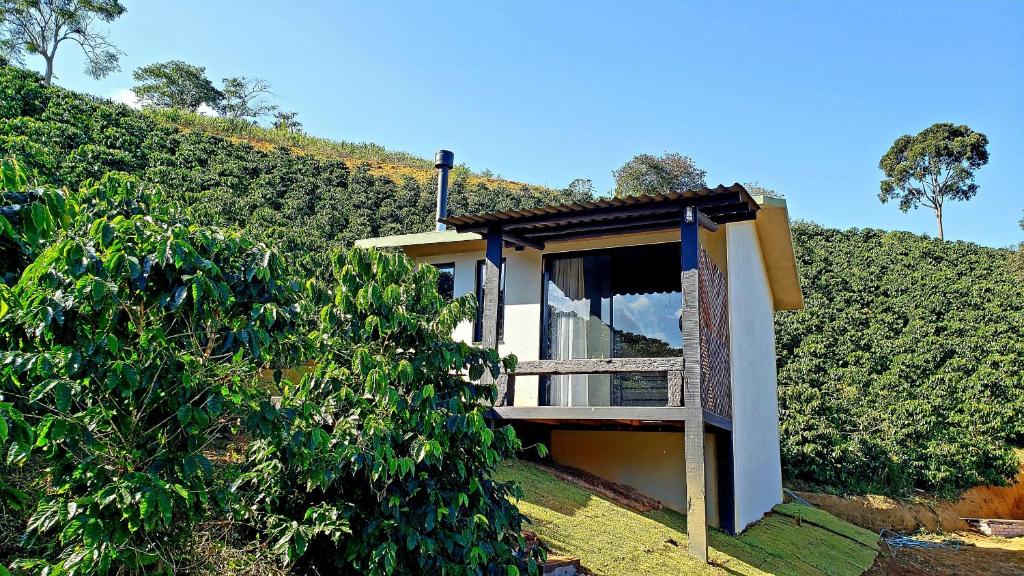 een huis met een balkon in een heg bij Hospedagem Bangalô Patrimônio da Penha in Divino de São Lourenço