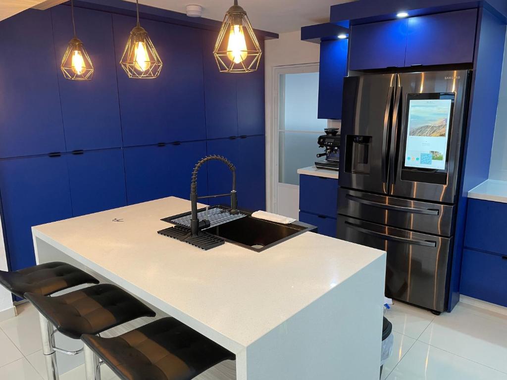 una cocina con armarios azules y una isla de cocina con nevera. en Luquillo Mar Paradise en Luquillo