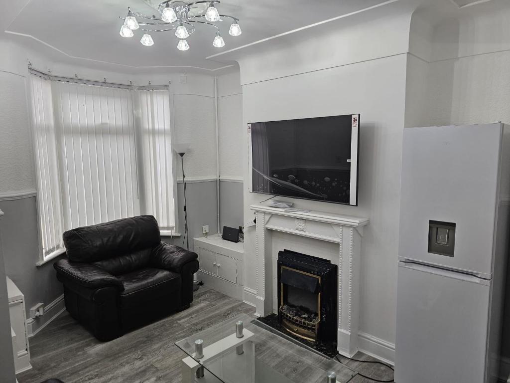 een woonkamer met een televisie, een stoel en een open haard bij Bridge Apartment in Liverpool