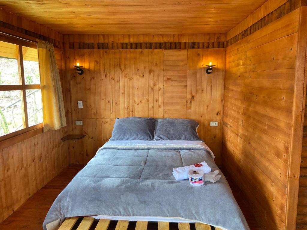 1 dormitorio con 1 cama en una habitación de madera en La madriguera de Guatavita, en Guatavita