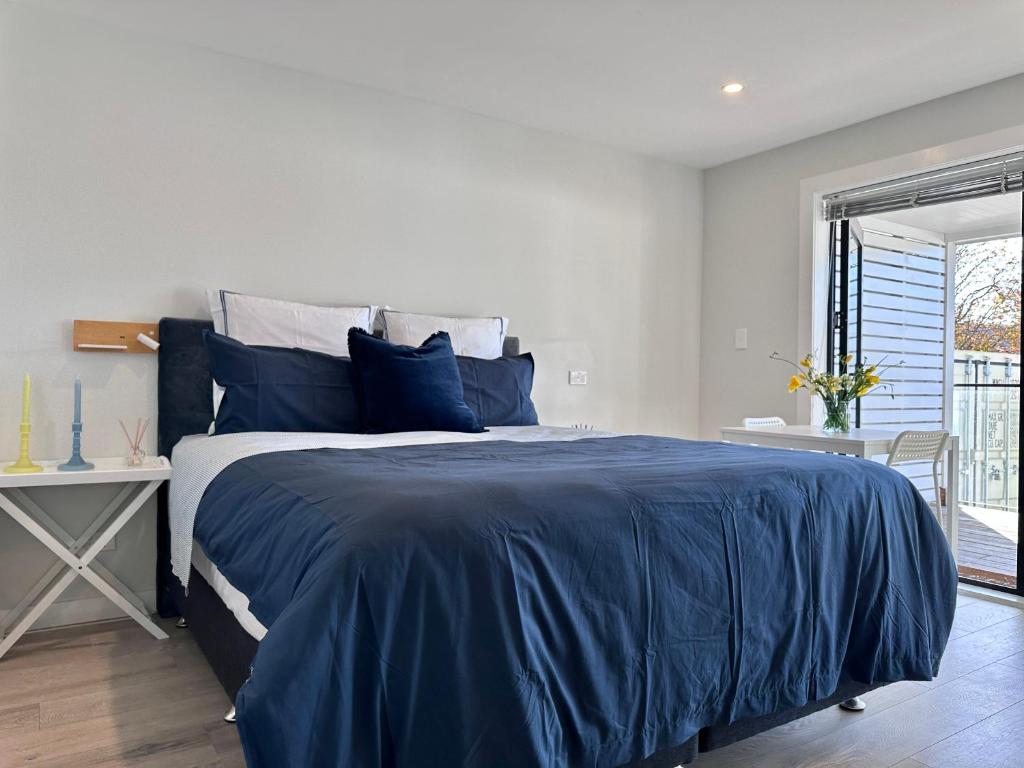 una camera con un letto blu e una finestra di 66 Express luxury apartment in New Market Our apartments has Self-checkin System ad Auckland