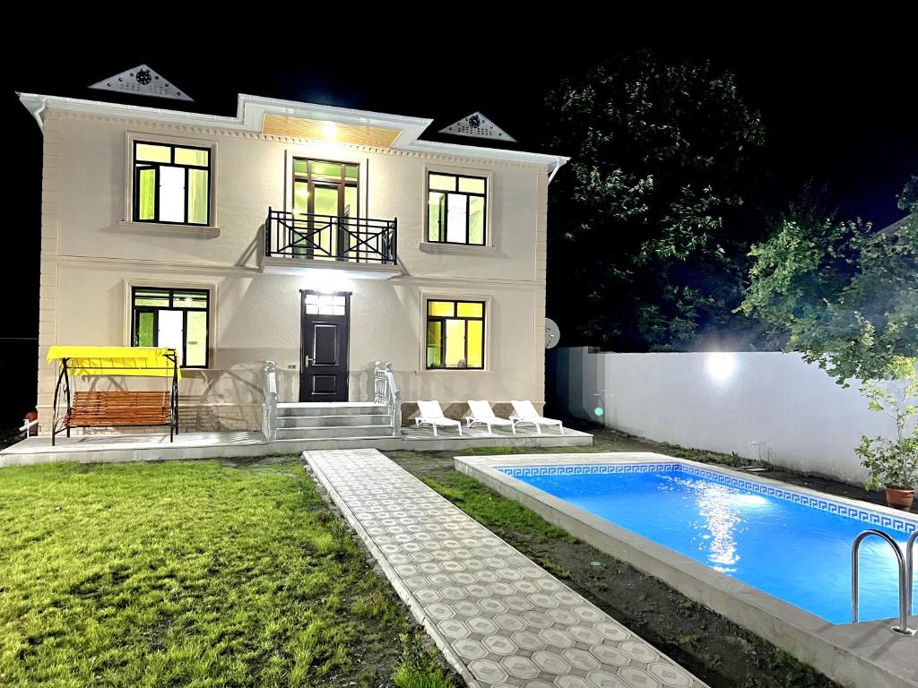 a white house with a swimming pool in front of it at Gabala villa in the center in Gabala