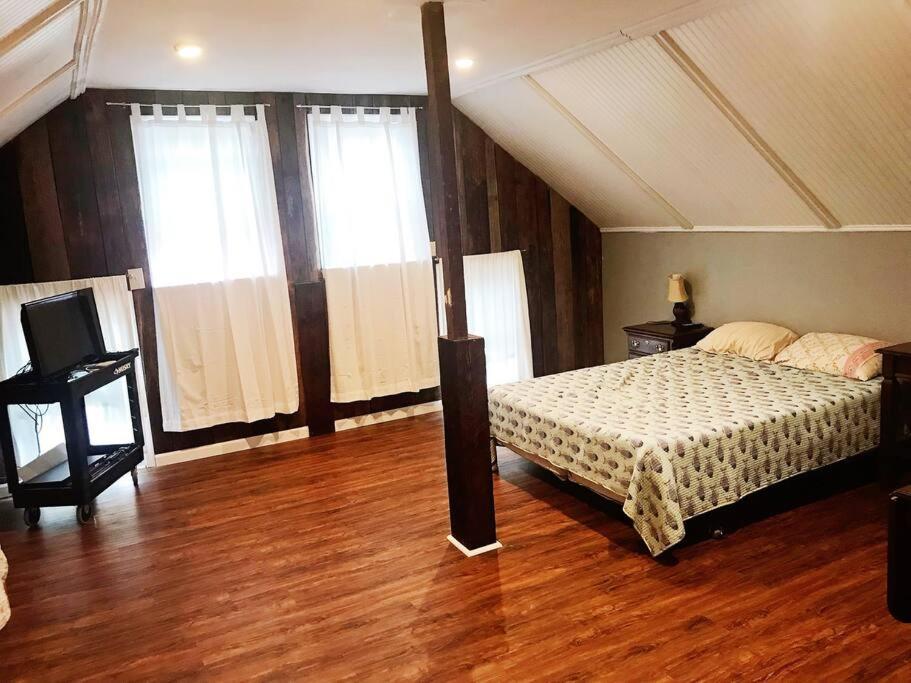ein Schlafzimmer mit einem Bett sowie Holzböden und -fenster in der Unterkunft Eden Farm: Private Studio Minutes from Salisbury in Eden