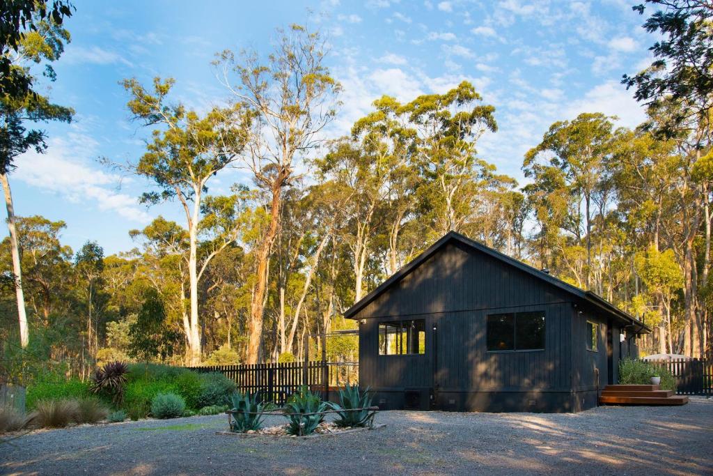 a small black shed with a fence and trees at Ablac House in Glenlyon