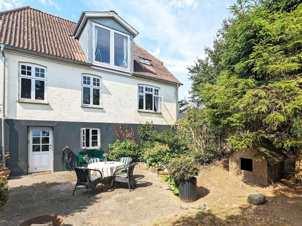 een wit huis met een tafel en stoelen in een tuin bij Holiday home Søby Ærø II 