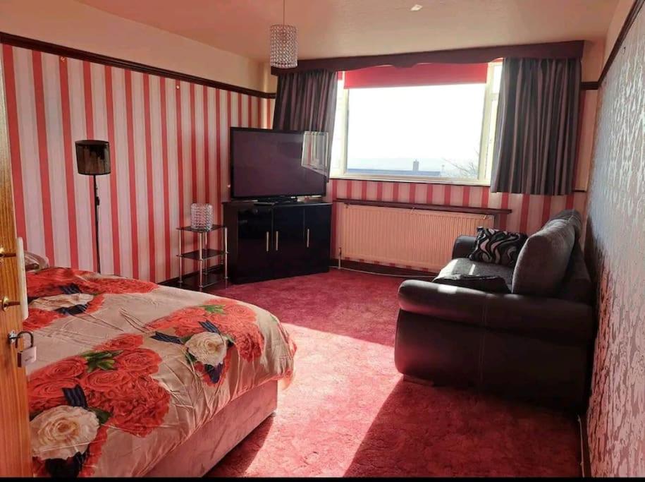 een slaapkamer met een bed, een bank en een televisie bij Home Away From Home in Nottingham