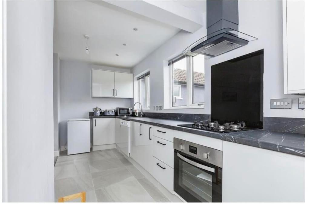 a kitchen with white cabinets and a stove top oven at 3 Bedroom House in Loughborough in Loughborough