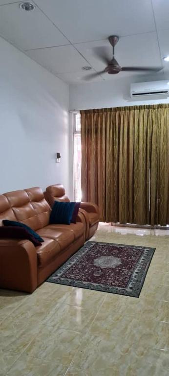 een woonkamer met een bruine leren bank en een tapijt bij NZ FAMILY HOMESTAY in Kota Bharu