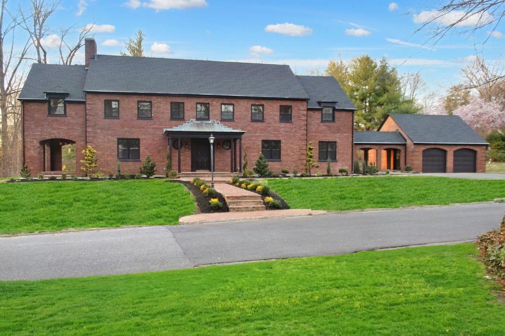 une grande maison en briques rouges avec une allée. dans l'établissement Estate Getaway, à Glen Cove