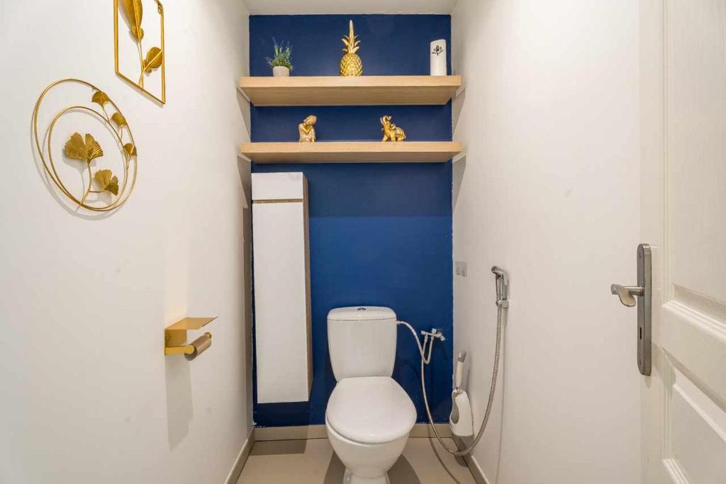 a bathroom with a toilet and a blue wall at Chambre 26m - Salon et kitchenette privé - WIFI in Woippy