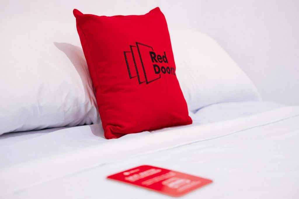 a red pillow on a white bed with a red sign at RedDoorz @ Kings Hotel near CSB Mall in Cirebon