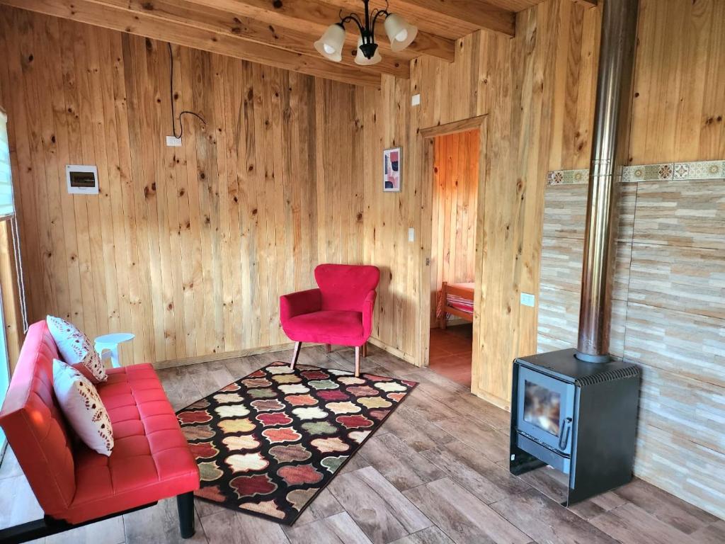 sala de estar con silla roja y fogones en Cabañas Entre copihues en Osorno