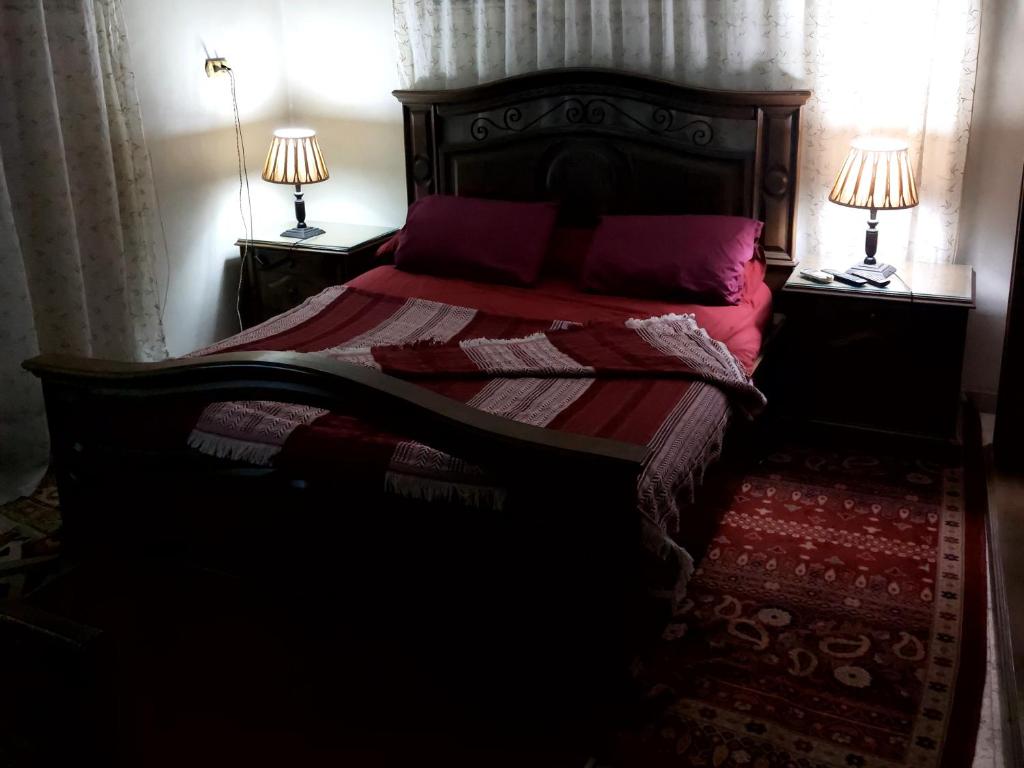 ein Schlafzimmer mit einem Bett mit roter Bettwäsche und zwei Lampen in der Unterkunft Safe House in Kairo