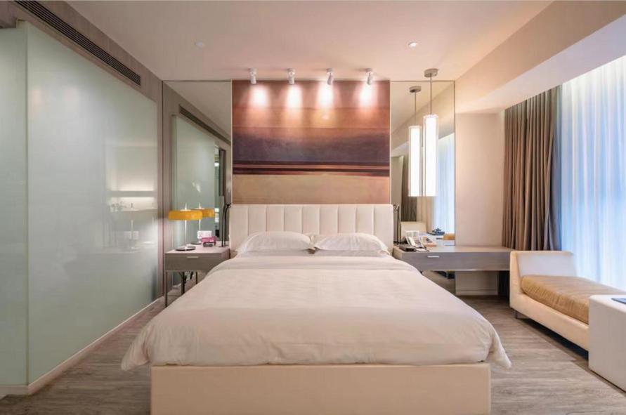 a bedroom with a large white bed and a desk at Metropolo, Hangzhou, East Railway Station in Hangzhou