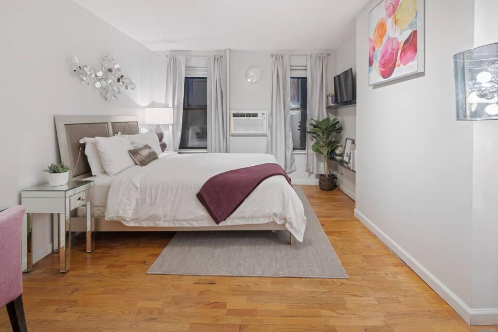 a white bedroom with a large bed and a table at Studio Haven in Times Square & Nearby Restaurants in New York