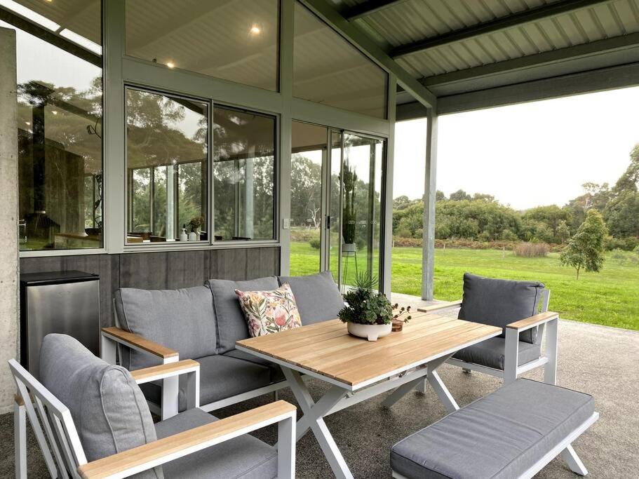 een afgeschermde veranda met een houten tafel en stoelen bij Isle of Kilcarnup in Margaret River Town