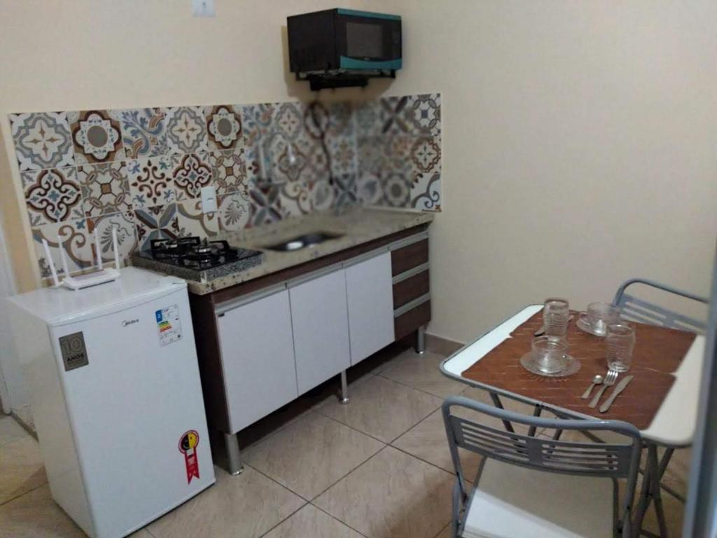 a small kitchen with a small table and a refrigerator at Loft Aconchegante no Centro de Niterói!! in Niterói