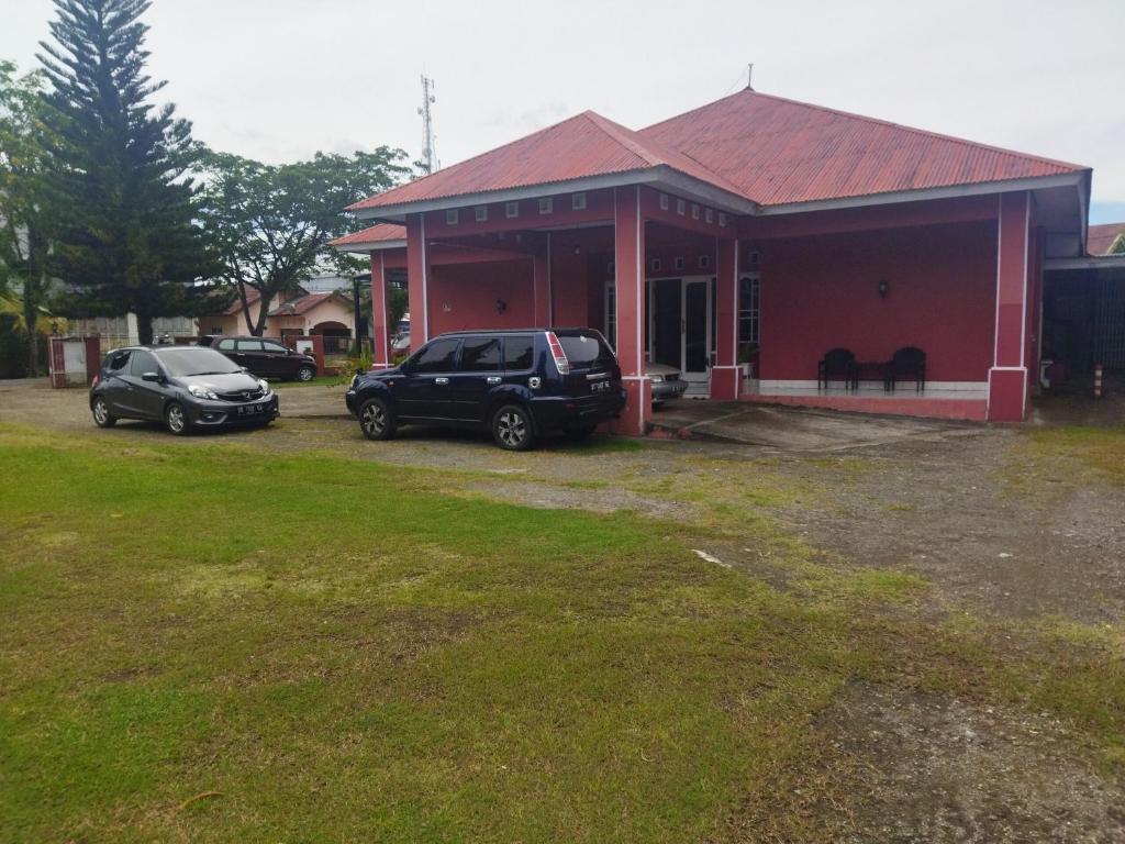 dwa samochody zaparkowane przed czerwonym budynkiem w obiekcie OYO 92775 Wisma Phinisi Syariah 