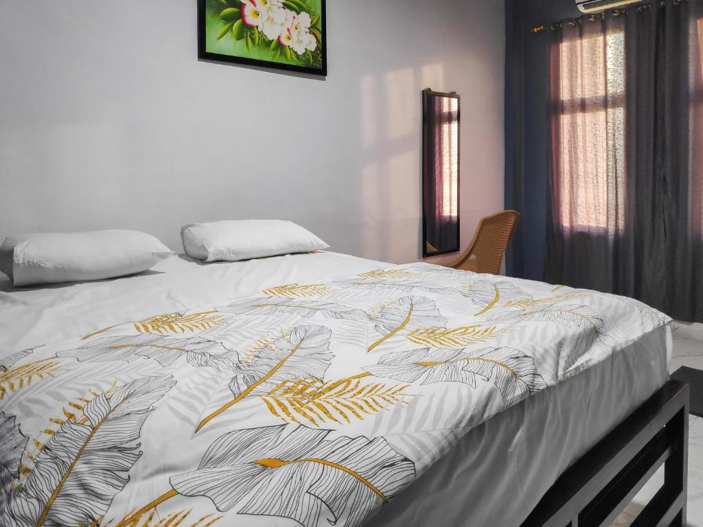 a bed with a white and gold blanket on it at RedDoorz at Perdagangan Simalungun in Perdagangan-tomuon