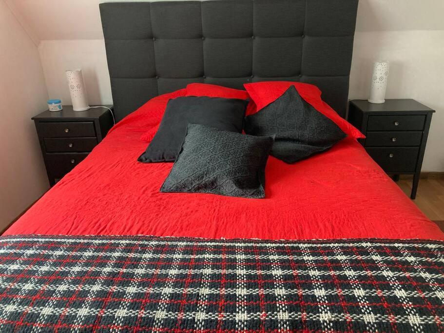 a bed with a red blanket and black pillows at Villarrica: lago, volcán y parques naturales in Villarrica
