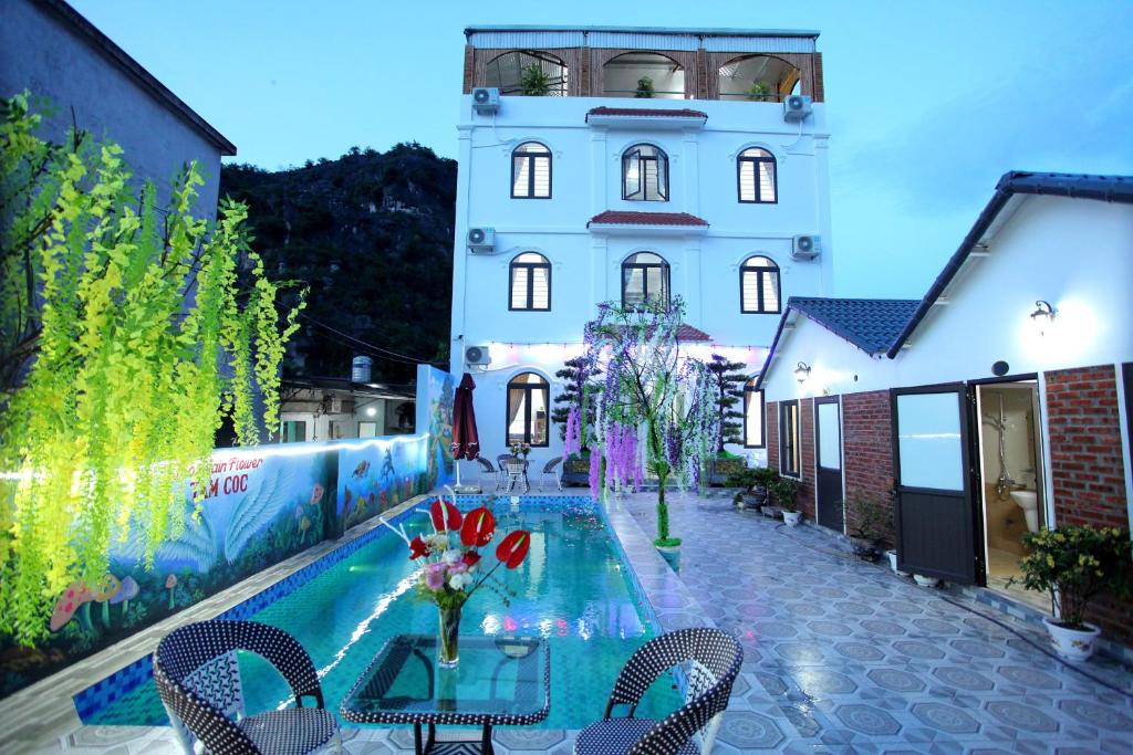 un edificio con tavolo e sedie accanto a una piscina di Tam Coc Mountain Flower Homestay a Vũ Lâm