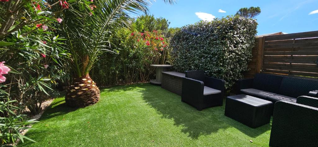 un jardin avec deux chaises et un banc en gazon dans l'établissement Studio avec jardin Fréjus, à Fréjus