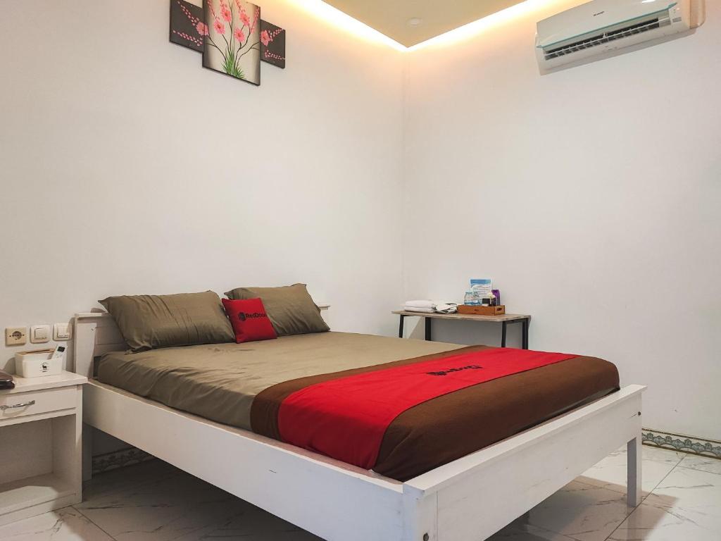 a bed in a white room with two night stands at RedDoorz Syariah at Naffa Homestay in Sarolangun
