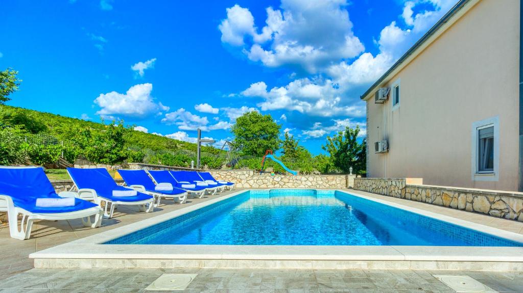 a swimming pool with blue chairs and a building at Villa My peace in Sičane