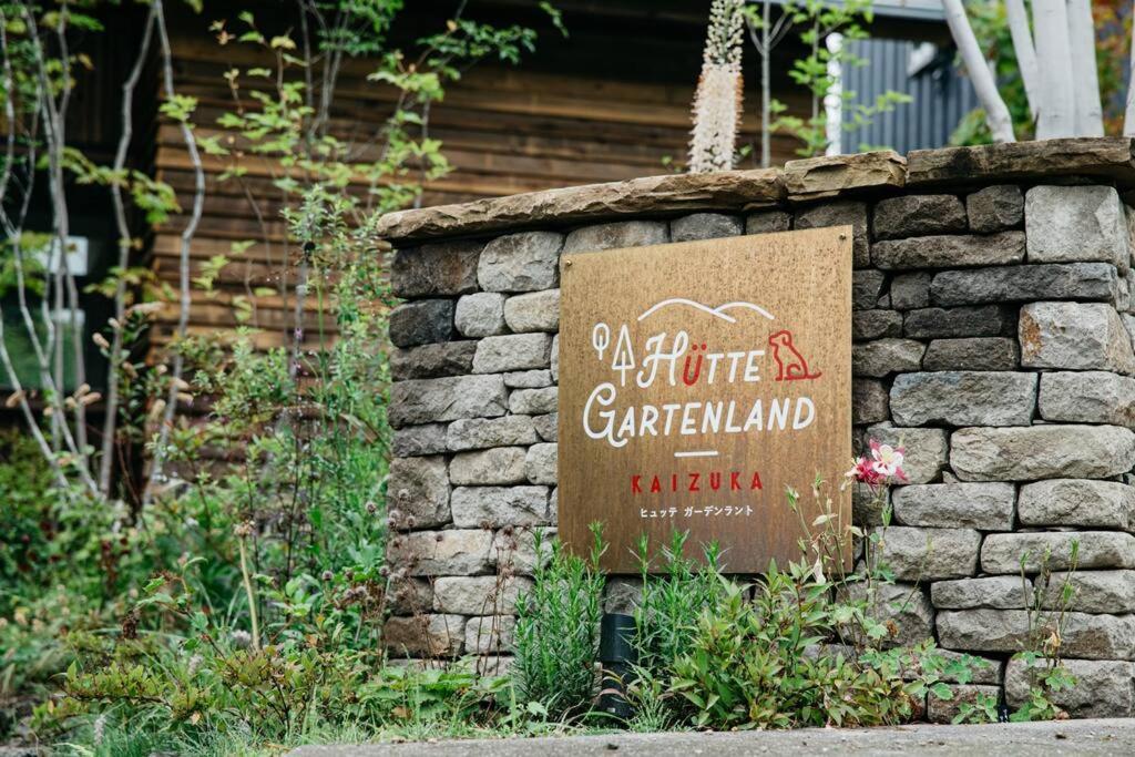 輕井澤的住宿－Hutte Gartenland -KAIZUKA- ヒュッテ ガーテンラント カイヅカ，花园中石墙上的标志