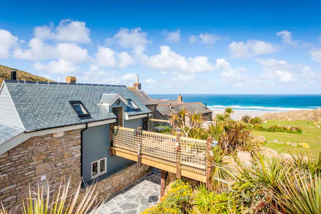 a house with a balcony with the ocean in the background at Sandpipers, Boutique Cottage With Wow Sea Views In Amazing Location in Sennen