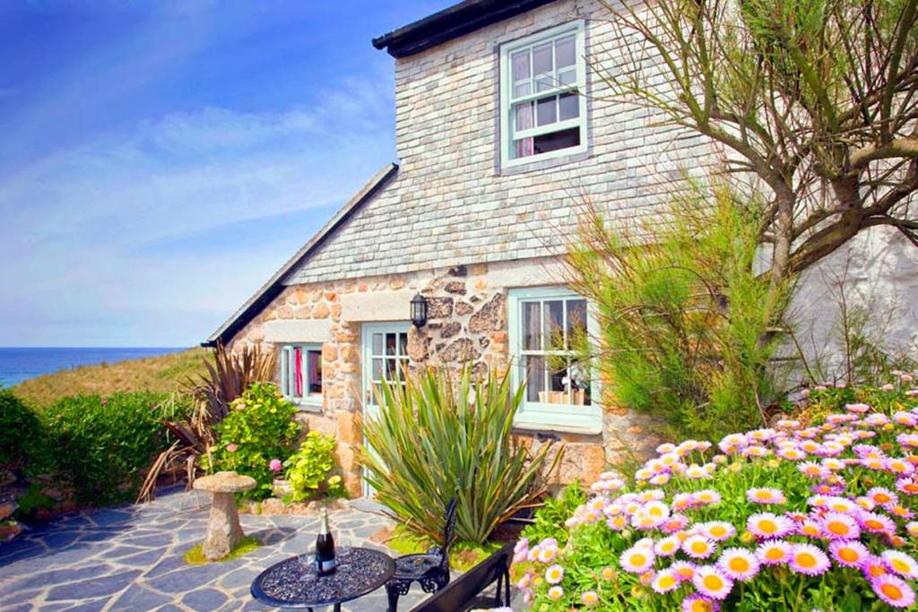 a house with a table and flowers in front of it at Little Petra, Cottage With Garden, Superb SeaViews in Amazing Location in Sennen