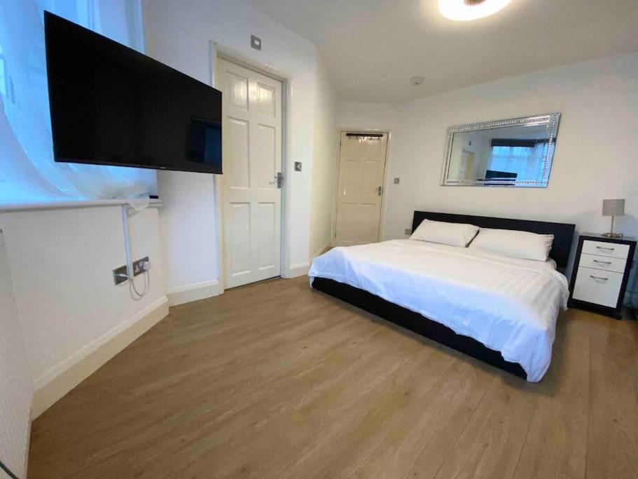 a bedroom with a bed and a flat screen tv at Spacious Studio 30 mins from Luton free parking in The Hyde