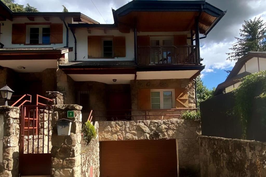 uma casa com um portão e uma parede de pedra em La Candela em Cercedilla