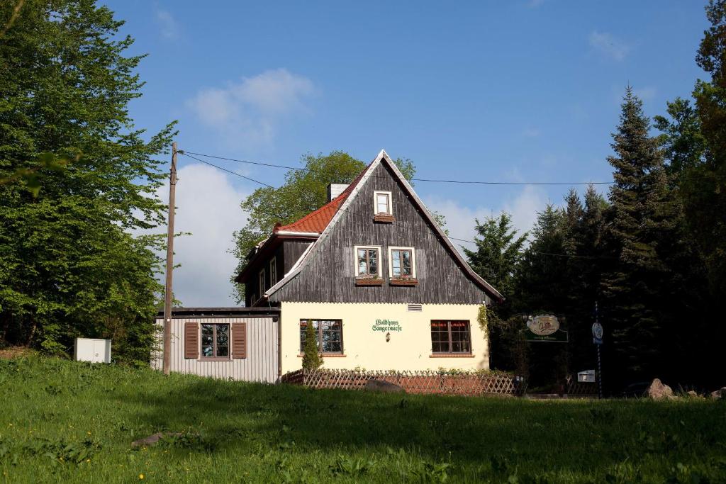 ein Haus mit einem schwarzen Dach auf einem grünen Feld in der Unterkunft Sängerwiese in Eisenach