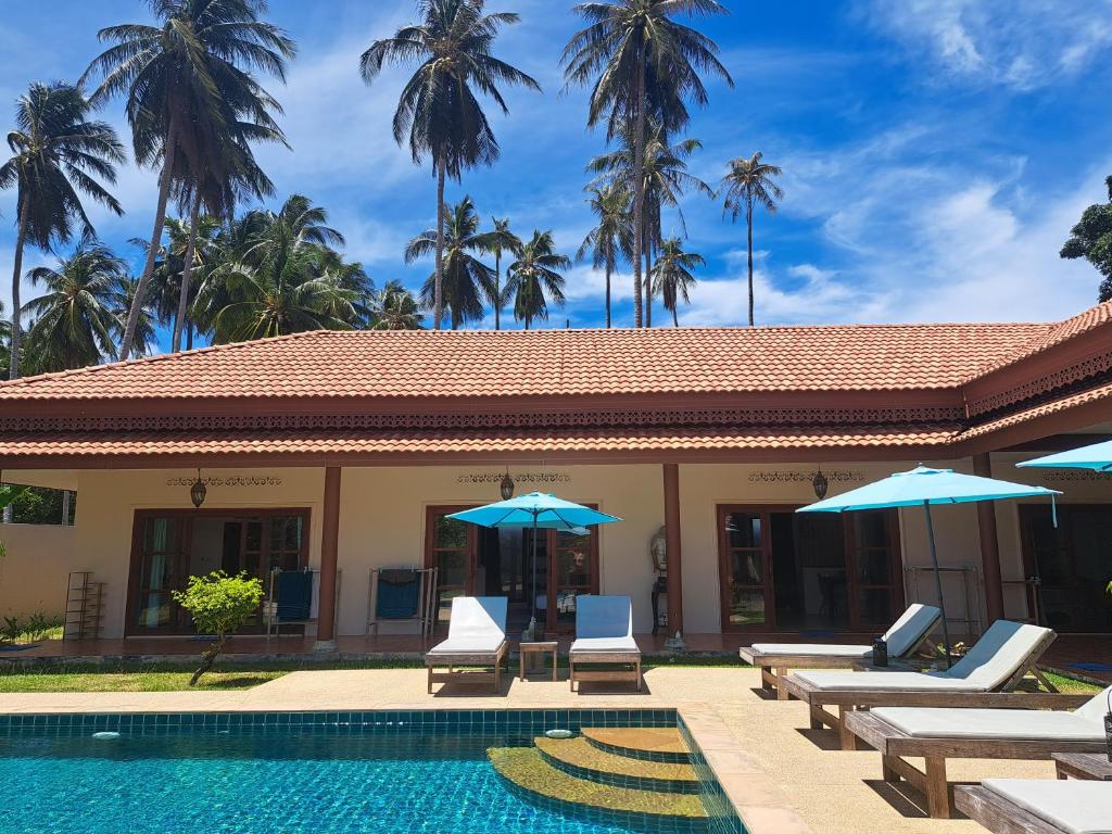 a resort with a swimming pool with chairs and umbrellas at Laura Guest House Samui in Lamai