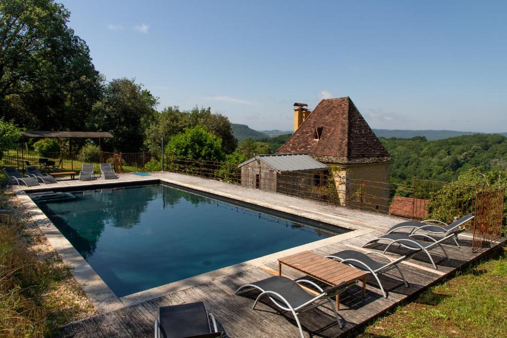 una piscina con sillas y una casa en Tour Milou, en Beynac-et-Cazenac