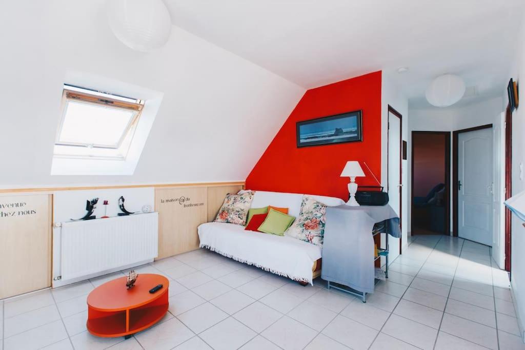 a living room with a couch and a red wall at Appartement - Plogoff Pointe du Raz in Plogoff