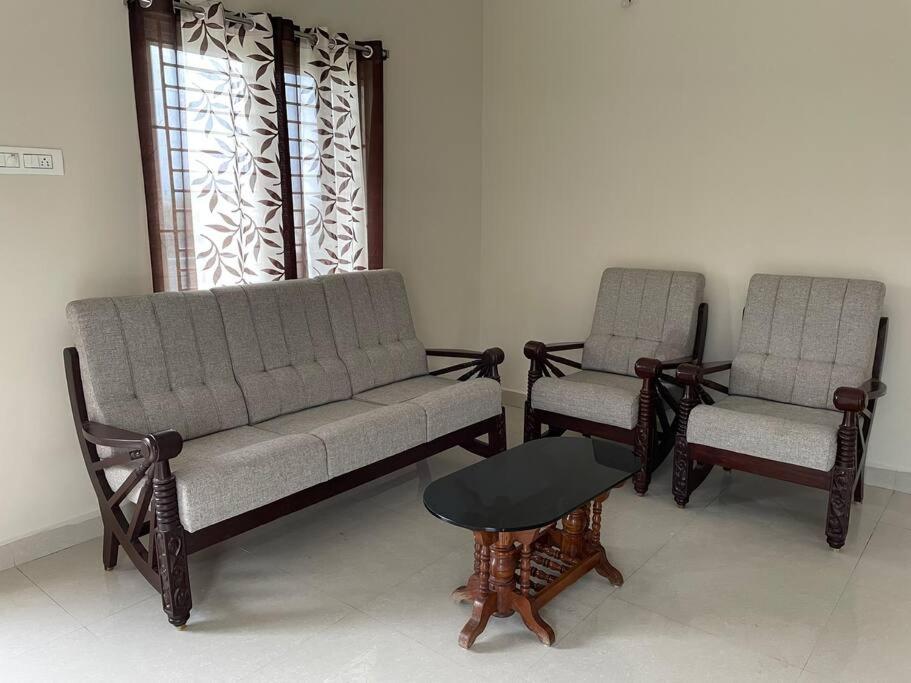 two chairs and a couch and a table in a room at SSN Home Stays in Tirupati Near Alipiri in Tirupati