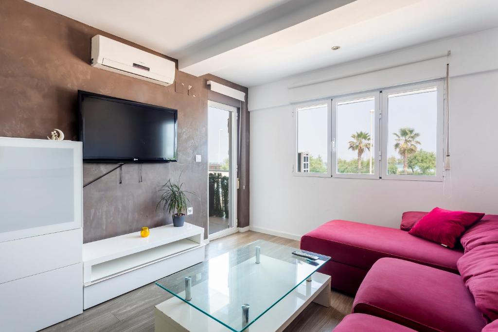 sala de estar con sofá rojo y TV en Fantástico apartamento en primerísima línea playa, en La Torre