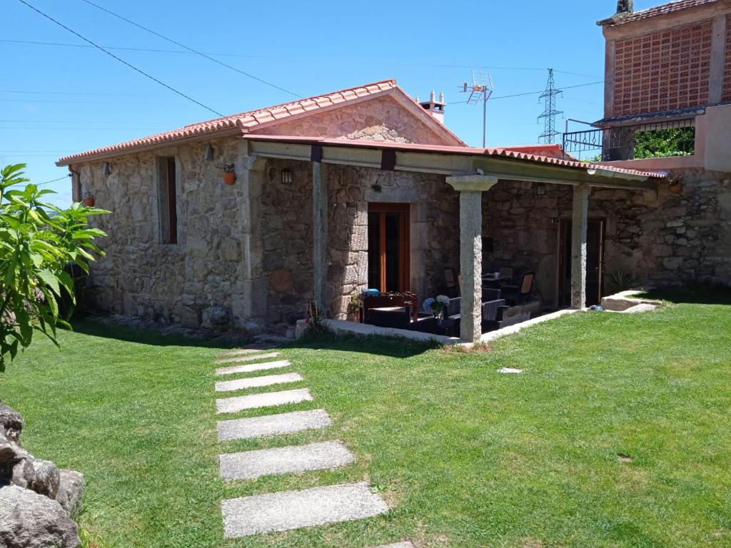 una casa de piedra con un patio de hierba delante de ella en O Enxidro en Rois