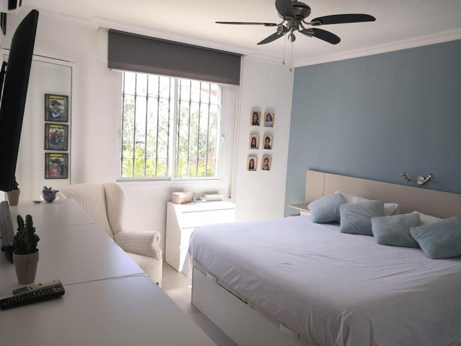 a white bedroom with a bed and a ceiling fan at Preciosa casa de lujo con piscina-150m de la playa in Almería