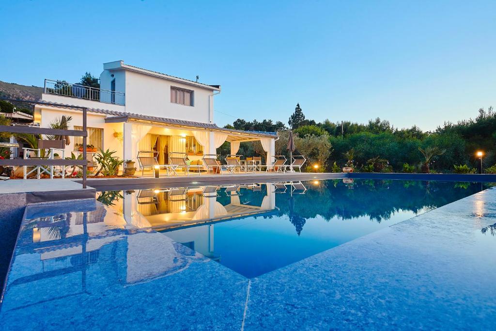 a villa with a swimming pool at dusk at Villa Antonella - Pool and Sea view in Castellammare del Golfo