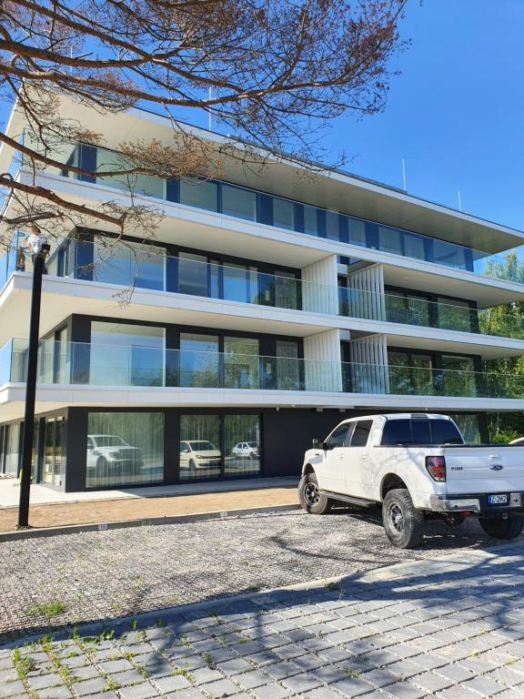 a white truck parked in front of a building at Sea & Lake Apartament 17, 317 Molo Mielno Sosnowy Las 15 in Mielno