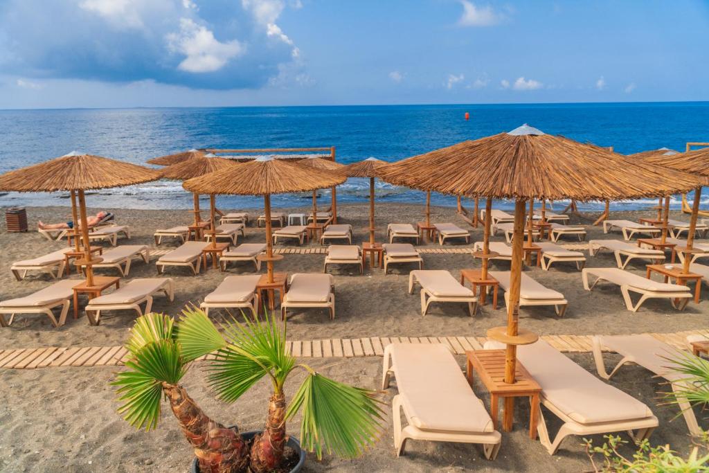uma praia com cadeiras e guarda-sóis e o oceano em Tylissos Beach Hotel - Adults Only em Lerápetra