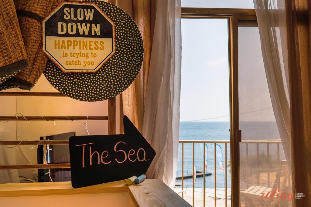 Un signe qui dit ralentir le bonheur à côté d'une fenêtre dans l'établissement A magical getaway by the sea, à Marsalforn