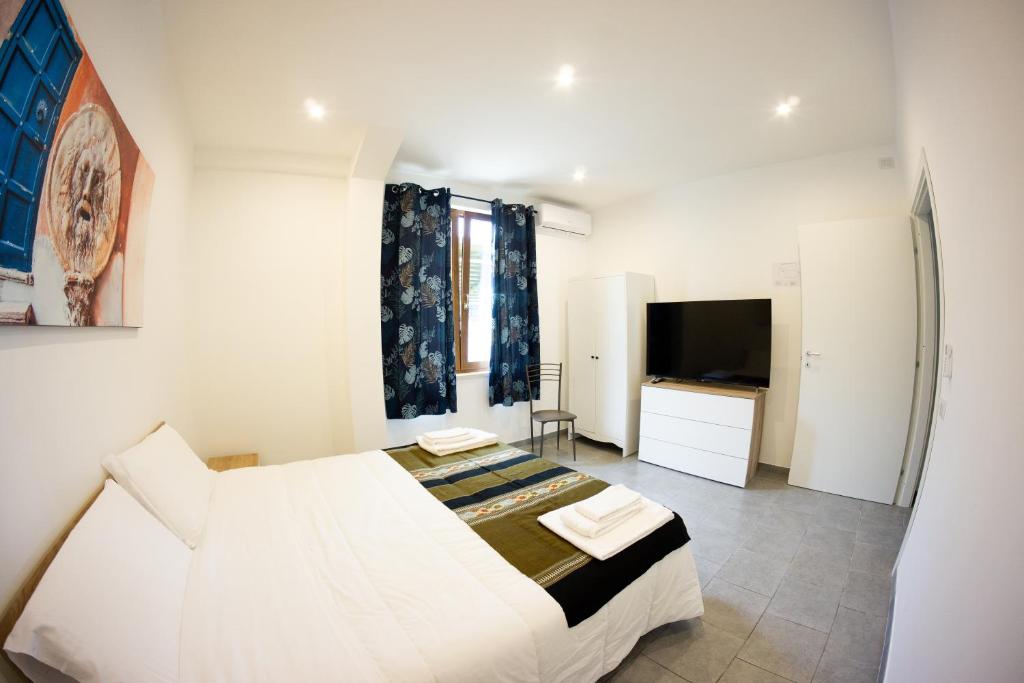 LA PIANETTA case vacanze في باليدورو: غرفة نوم بيضاء فيها سرير وتلفزيون